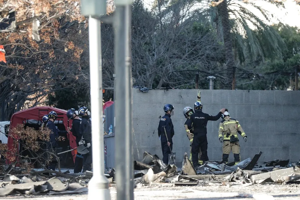 Agentes de la Policía Científica y bomberos observan este sábado el edificio incendiado en el barrio de Campanar de Valencia.