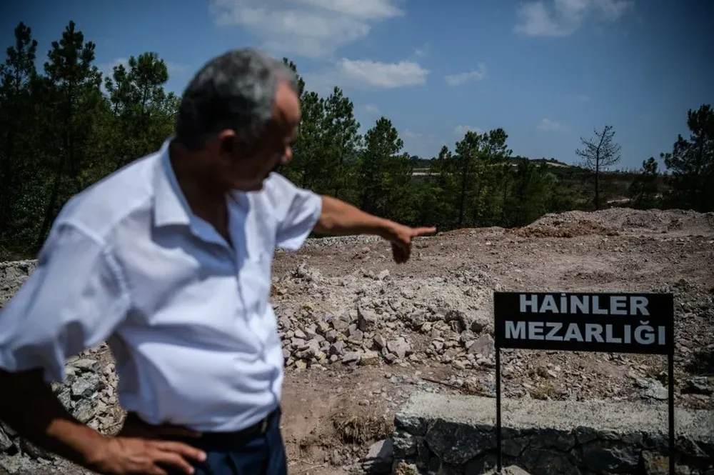 Un hombre señala el cartel que dice cementerio de los traidores