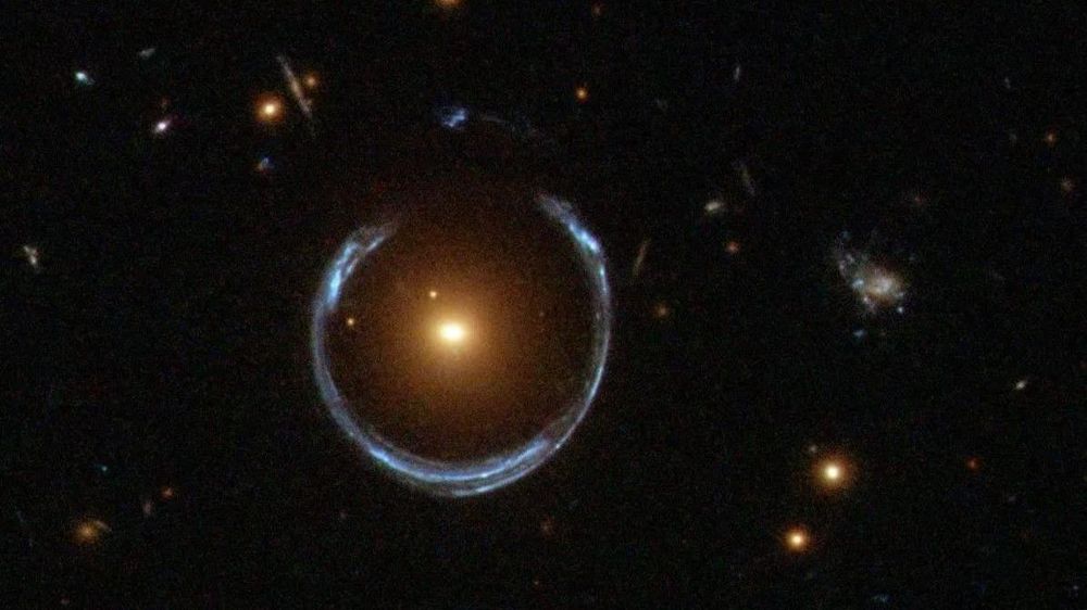 La lente gravitacional ha permitido al telescopio Hubble capturar la distante galaxia de la Herradura Azul, magnificada por la galaxia Roja Luminosa que se encuentra frente a ella.