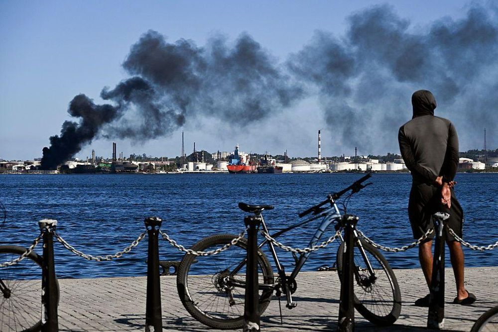Un hombre observa la columna de humo que emana de la refinería Ñico López en La Habana.