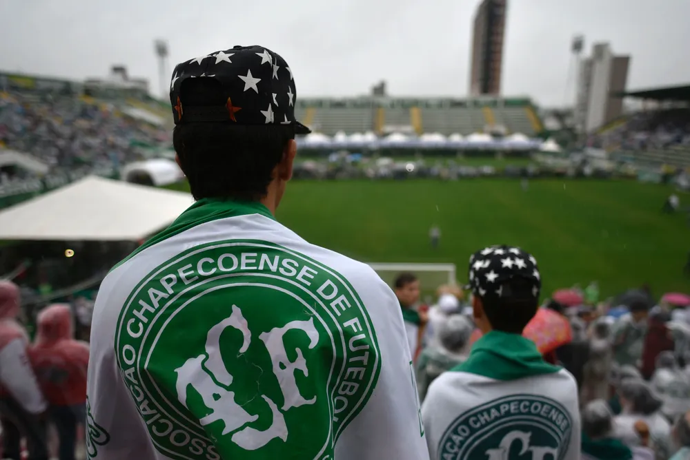People await for the arrival of the funeral cortege of the players of Brazilian football team Chapecoense Real killed in a plane crash in the Colombian mountains, at the Arena Conda stadium in Chapeco, in the southern Brazilian state of Santa Catarina, on December 3, 2016. The first of two Brazilian air force planes carrying the remains of a football team killed in a plane crash arrived Saturday in the city of Chapeco in southern Brazil. / AFP / DOUGLAS MAGNO