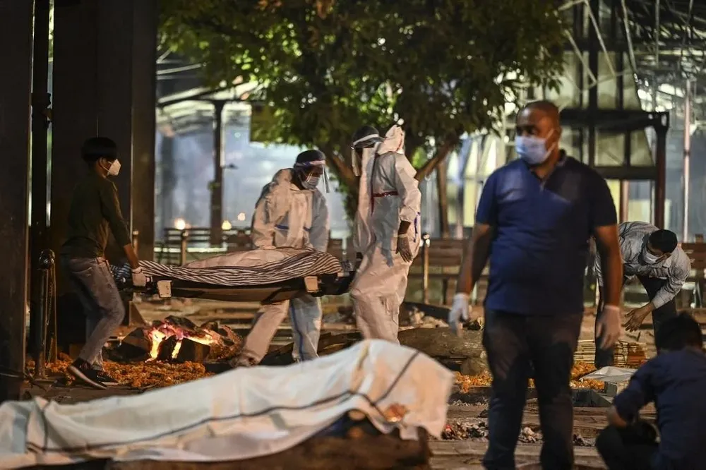 Los familiares y el personal médico llevan el cadáver de una víctima del covid-19 en el crematorio Nigambodh Ghat, a orillas del río Yamuna en Nueva Delhi.