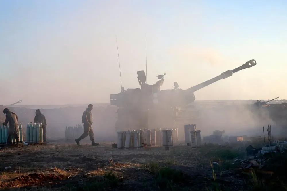 Los soldados israelíes disparan un obús autopropulsado de 155 mm hacia la Franja de Gaza desde su posición a lo largo de la frontera, este 18 de mayo