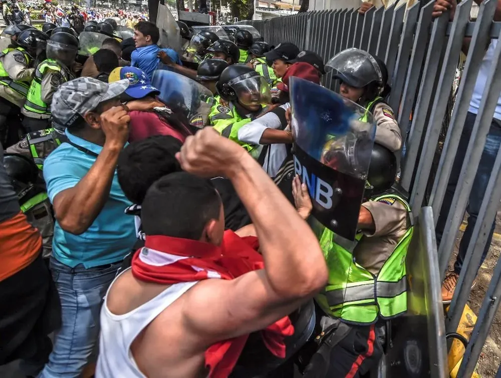 Opositores del gobierno de Venezuela chocan con agentes de la policía antidisturbios durante una protesta