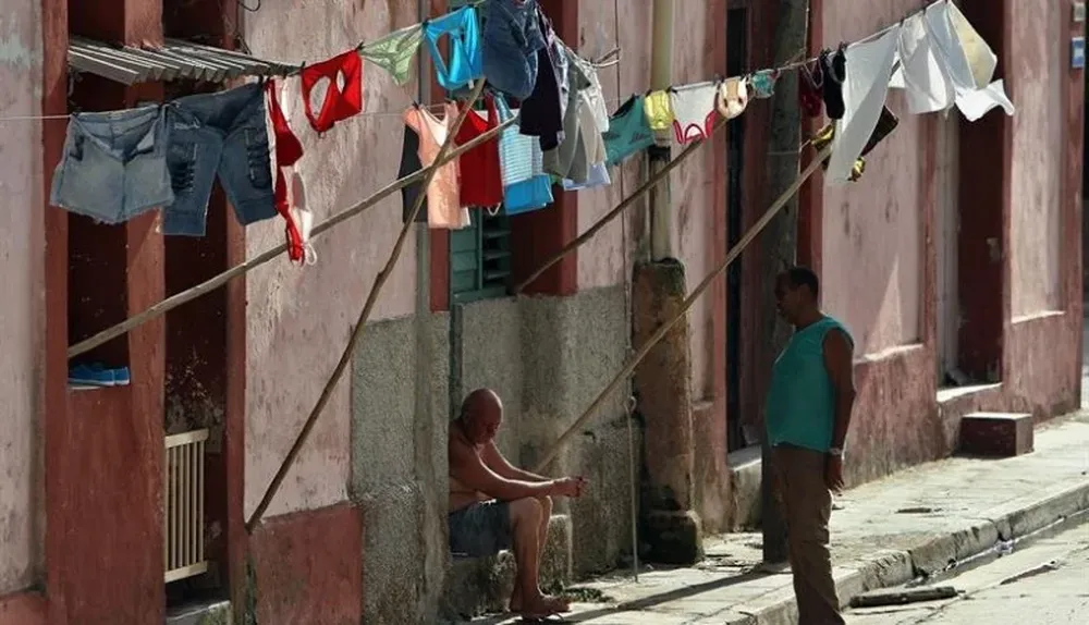 Cuba. Dos hombres conversan bajo la ropa extendida para secar, en Matanzas