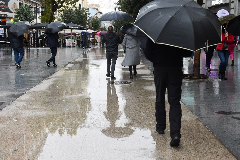 Un grupo de personas se protegen de la lluvia en Madrid, España. EUROPA PRESS