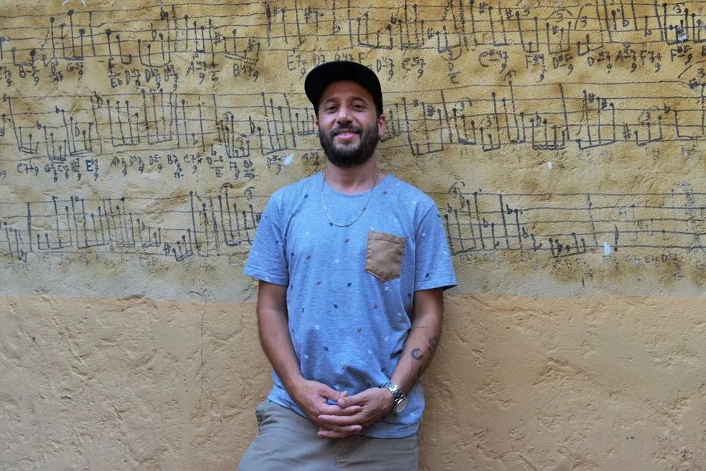 Leandro Quiroga, productor de Medio y Medio, frente a un muro histórico con una composición de Hermeto Pascoal