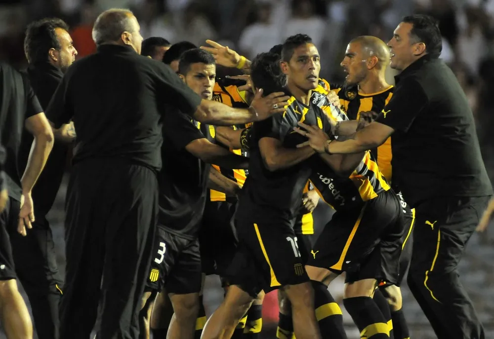 Alejandro Astesiano (a la derecha) como guardia de Peñarol en el tumulto entre jugadores de Nacional y Peñarol por la Copa Antel de 2014