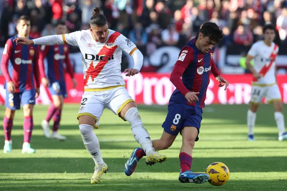 El defensa uruguayo del Rayo Vallecano Pacha Espino lucha por el balón con el centrocampista del FC Barcelona Pedri