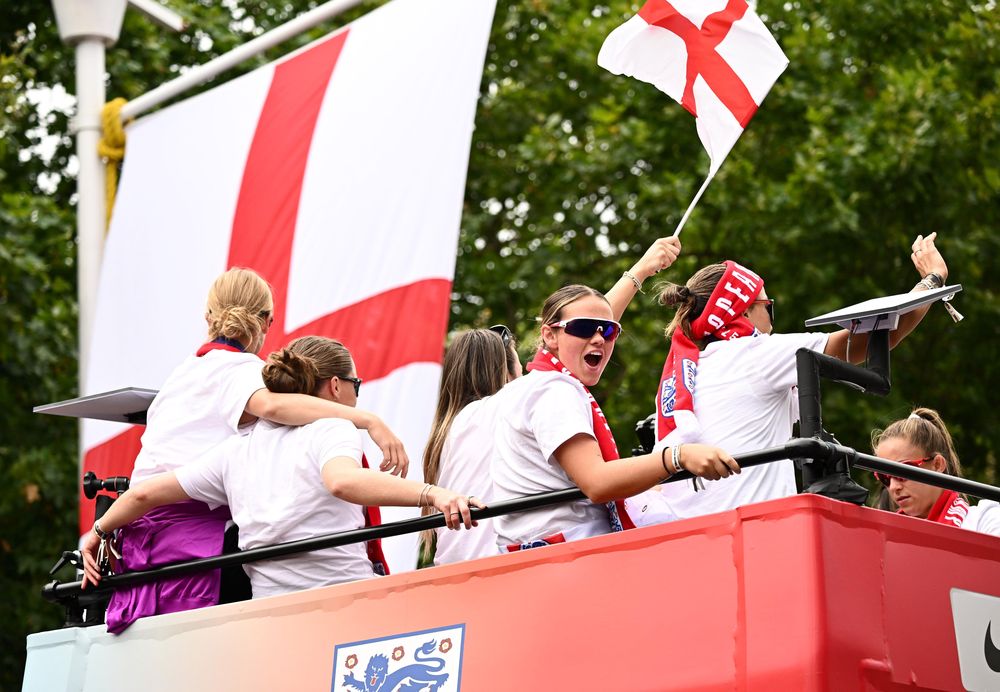 Las jugadoras de fútbol de Inglaterra celebran junto a la bandera de la Cruz de San Jorge durante el desfile de la victoria de las Leonas el 29 de julio.