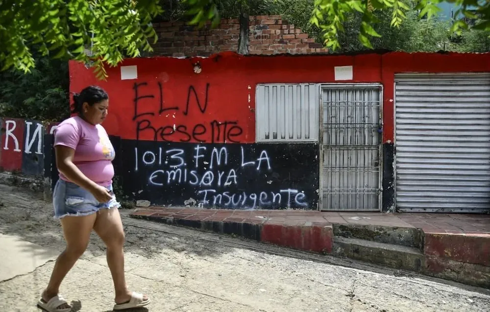 Una mujer pasa frente a una pintada que propagandiza la radio clandestina del ELN.