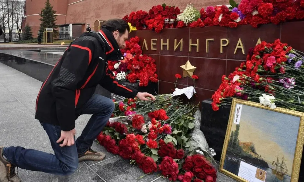 En el Kremlin (Moscú) un hombre se inclina para honrar a las víctimas en una piedra que recuerda a Leningrado, anterior nombre de la ciudad donde ayer sucedió el ataque.