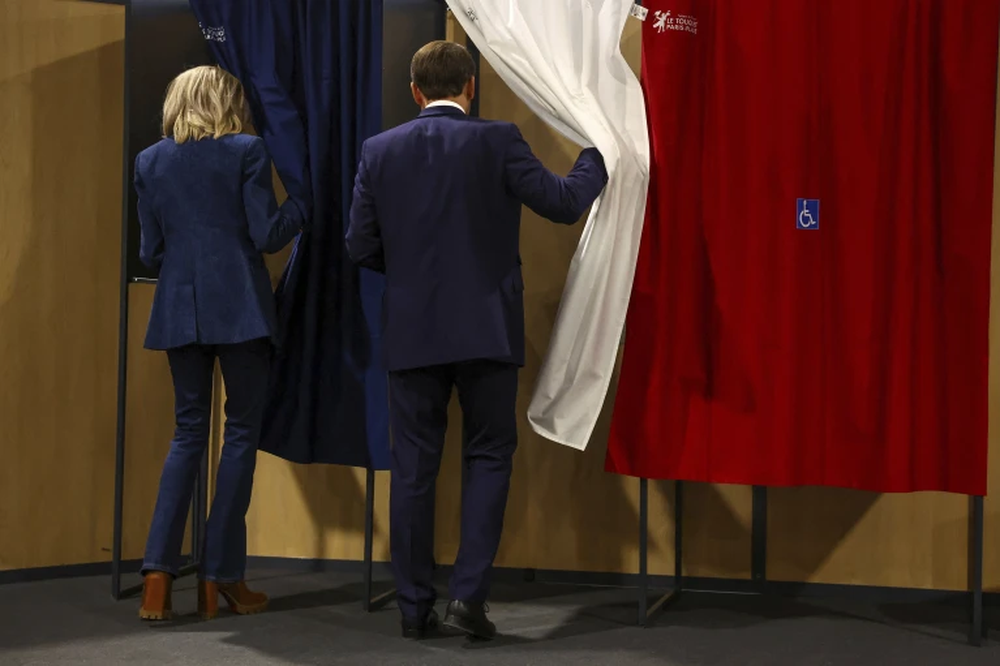 El presidente francés Emmanuel Macron y su esposa Brigitte Macron entran en una cabina de votación durante las elecciones europeas
