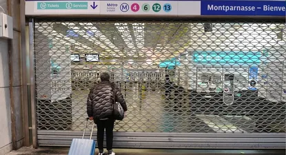 Una mujer se para frente a la puerta cerrada de una estación del metro de París
