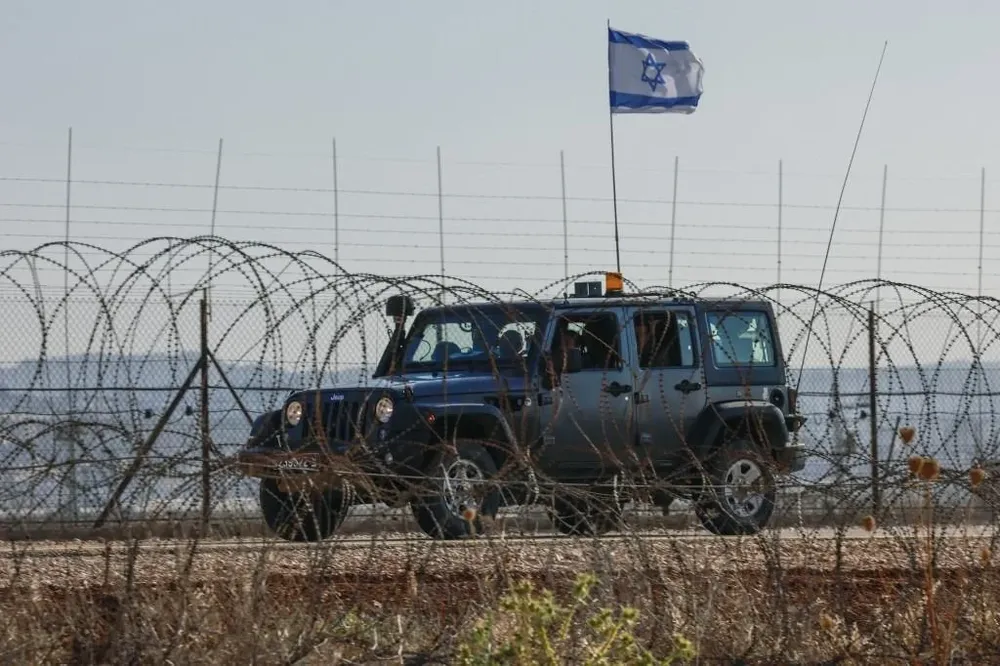 Un vehículo militar israelí patrulla una calle en Cisjordania ocupada