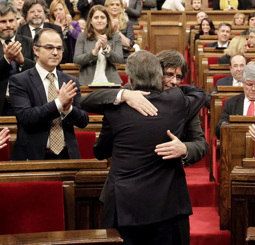 El presidente saliente, Artur Mas (de espaldas), abraza a su sucesor, Carles Puigdemont