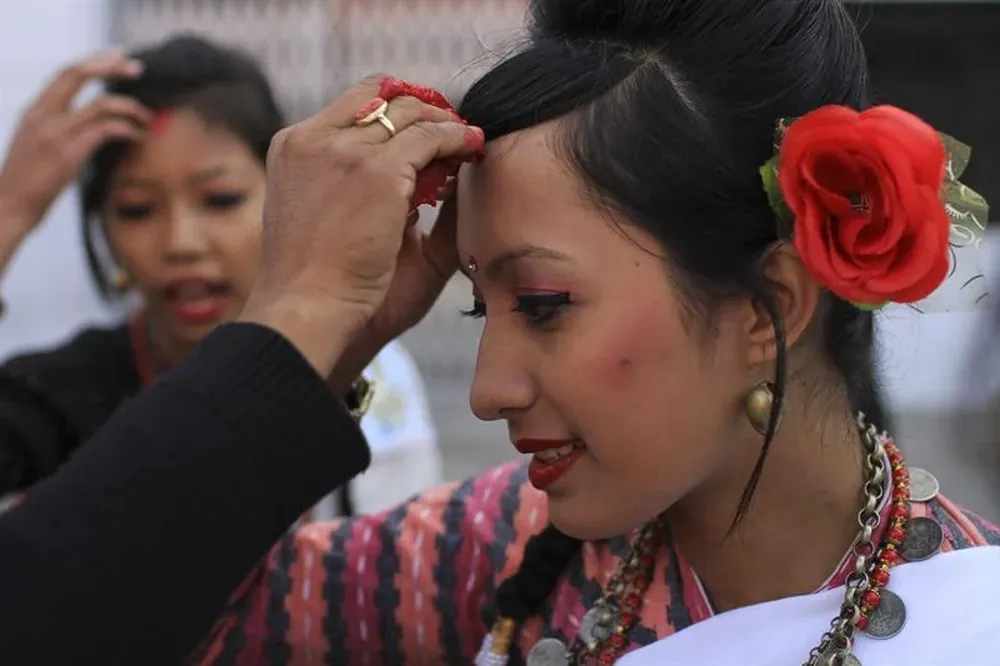 Nepal- Una joven de la minoría étnica Newari se coloca un tika (punto rojo en la frente)