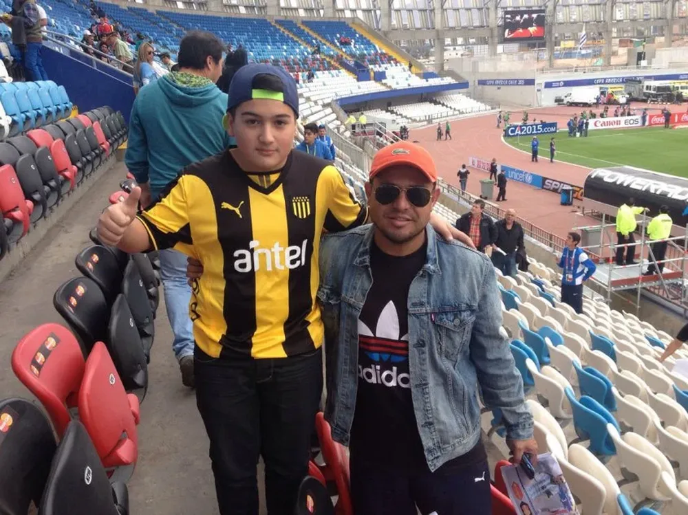 Enzo, con la camiseta de Peñarol, junto a su padre, José Luis, viendo a Uruguay