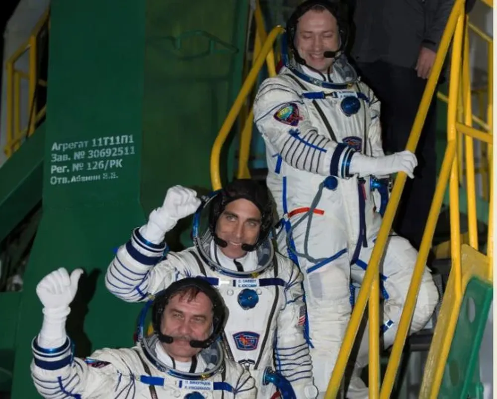 El ruso Alexander Misurkin (arriba), el estadounidense Chris Cassidy (medio), y el comandante de Soyuz Pavel Vinogradov, saludan desde la base del cohete Soyuz