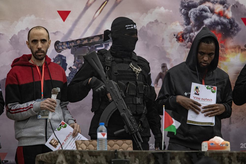 Terroristas de Hamás custodian a los rehenes israelíes Tal Shoham (I) y Avera Mengistu (D) antes de entregarlos a la Cruz Roja en Rafah, sur de la Franja de Gaza.