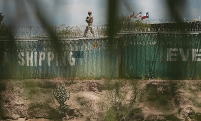 Un agente de la Guardia Nacional patrulla la frontera con México, desde lo alto de una línea de contenedores.