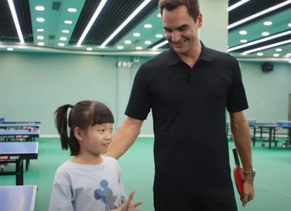 Roger Federer y una pequeña china campeona, a la que enfrentó en tenis de mesa