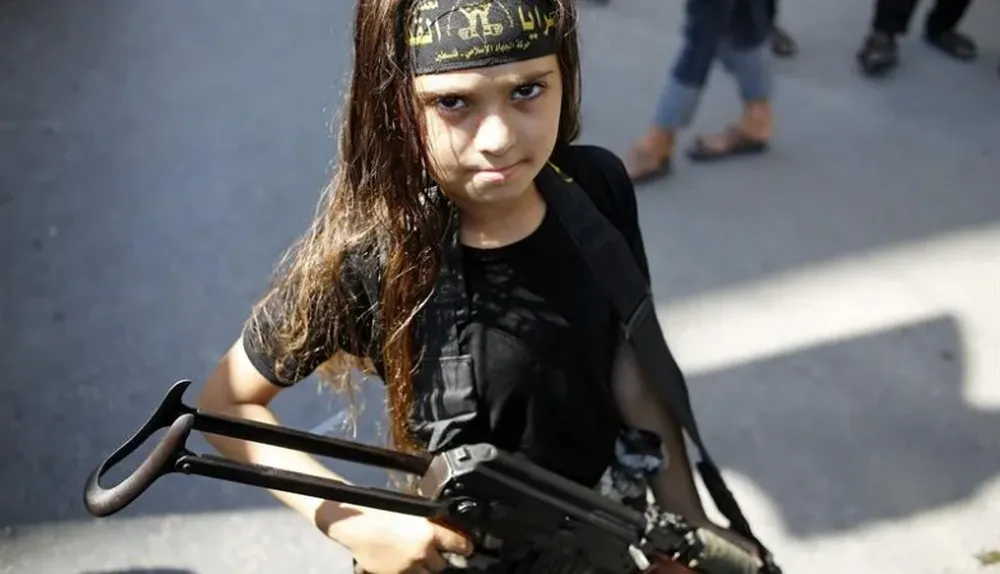 Franja de Gaza. Una niña sujeta un arma junto a luchadores palestinos