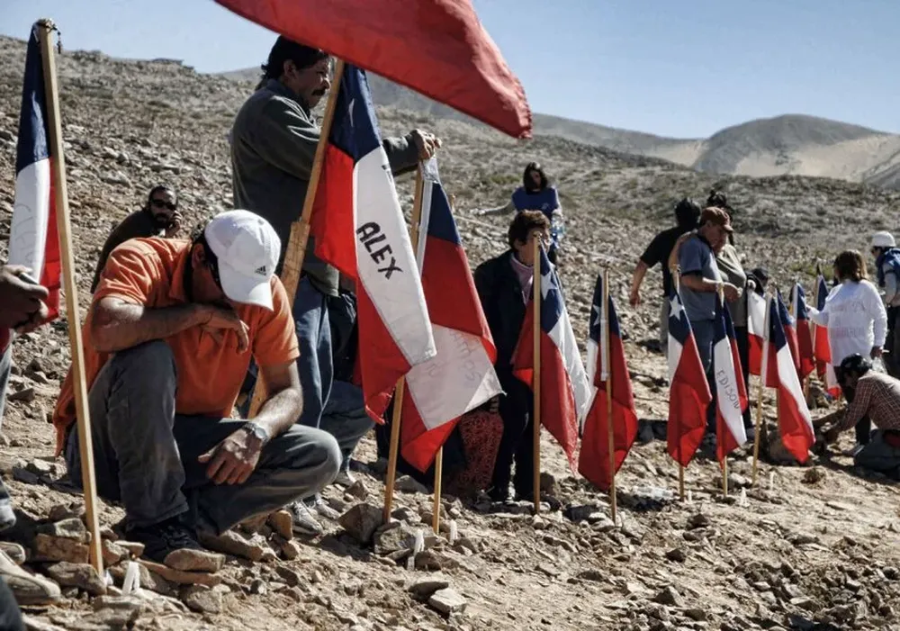 Cuando todavía no se sabía si los 33 estaban vivos, en la base de la mina instalaron banderas con sus nombres y rezaban por su aparición