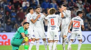 Maximiliano Gómez y sus compañeros de Nacional celebran la victoria ante la desazón del arquero de Cerro Largo, Pedro González, por el Torneo Apertura