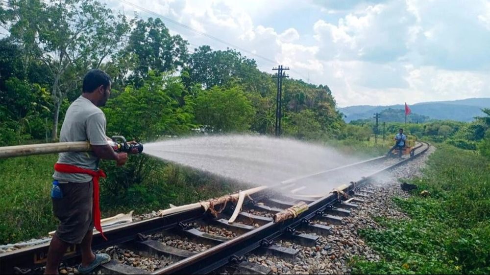Un operario ferroviario moja las vías de tren que se estaban derritiendo por el elevado calor en Tailandia