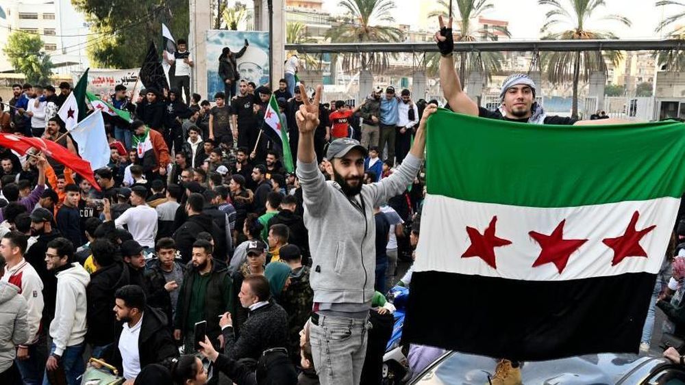 Multitudes de personas ondeando banderas en Damasco tras la caída del régimen de Assad en Siria.