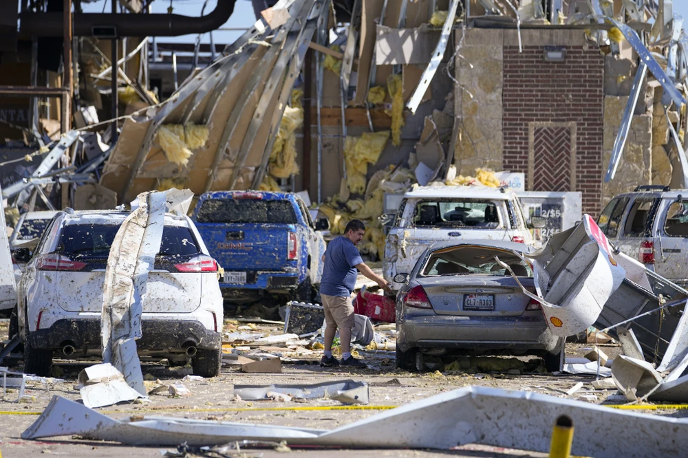 Un hombre mirando a un auto dañado después de que un tornado pasara el día anterior el domingo 26 de mayo de 2024 en Valley View, Texas.