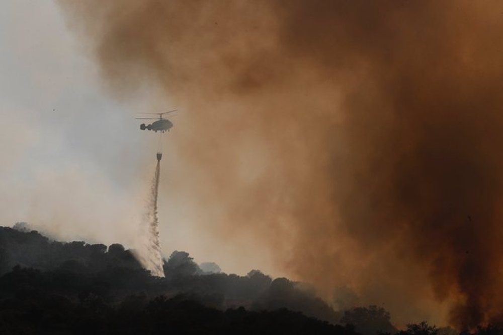 Un helicóptero de los servicios de emergencia de Madrid trabajan en el combate del incendio en Colmenar Viejo.