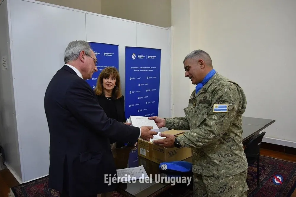 El director del Archivo General de la Nación, Alberto Umpierrez, entregando libros al coronel Pedro Gómez con la subsecretaria del Ministerio de Educación y Cultura, Ana Ribeiro
