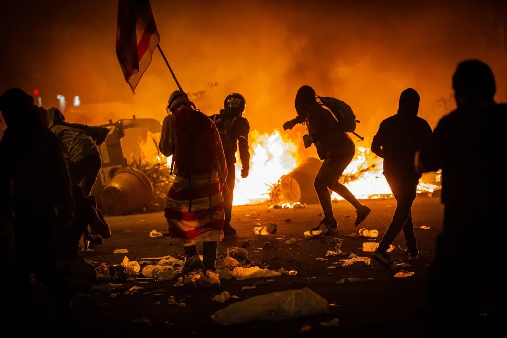 Varios manifestantes frente al fuego de una hoguera durante los disturbios en la Plaza de Urquinaona, en Barcelona a 18 de octubre de 2019.