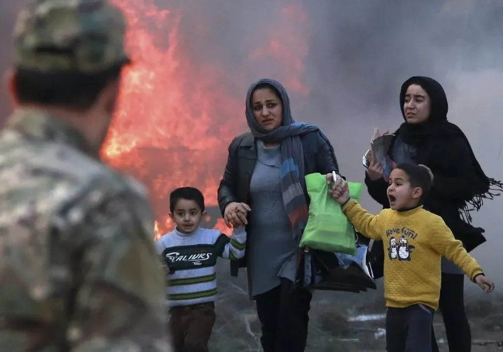Angela Merkel y Hans Peter Wollseifer miran guantes de cuero durante su visita a un stand de la feria en Alemania.