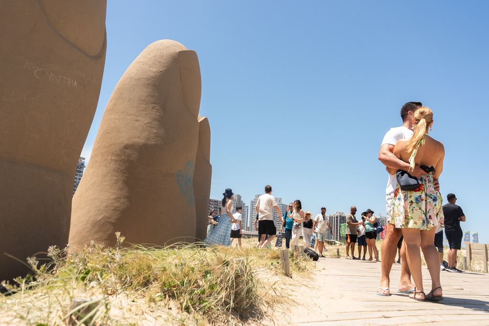 Turistas se toman fotografías junto a la escultura Los dedos este martes, en Punta del Este.&nbsp;
