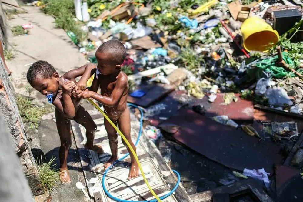 Brasil- Dos niños se bañan en medio de casas destruidas durante un desalojo en la favela Metro