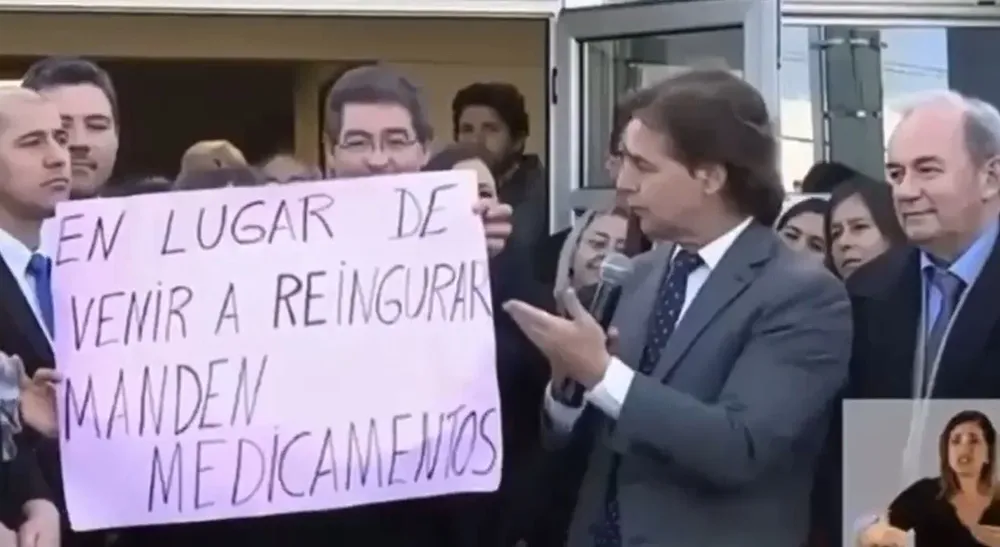 Lacalle Pou mostrando el cartel de la manifestante.