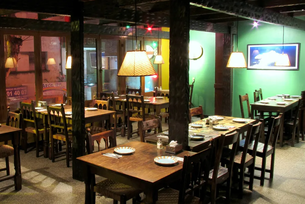 Decoración tabernera, con mesas de madera y ventanal a la calle San José