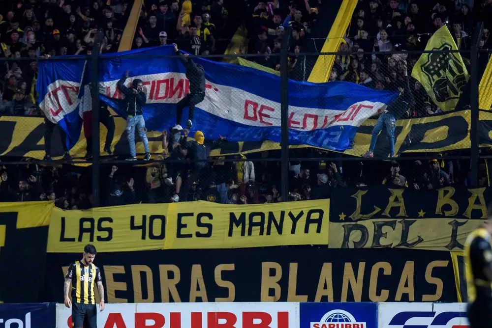 Bandera de Nacional exhibida por la hinchada de Peñarol