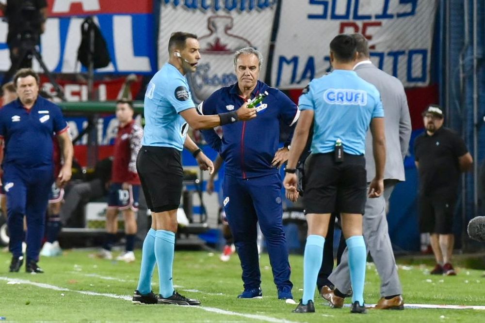 Esteban Ostojich entrega al encargado de seguridad una petaca que cayó desde la tribuna