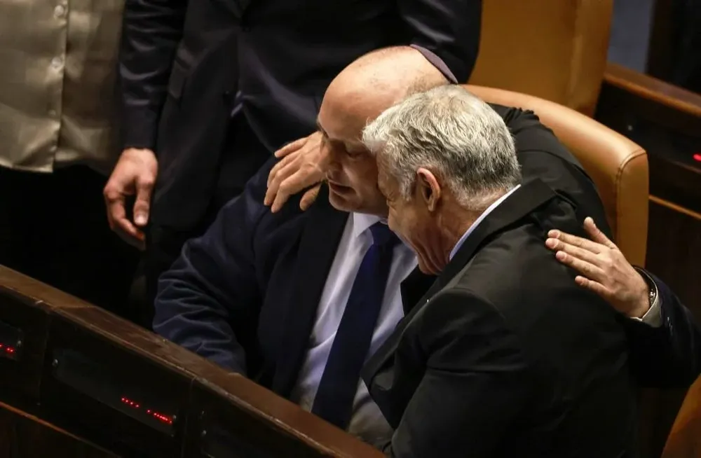 El canciller Yair Lapid, a la derecha, se abraza al saliente primer ministro Naftali Bennett, a la izquierda; tras la disolución del Parlamento en Jerusalem este jueves 30