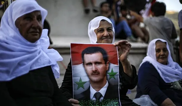 Votantes sirios con carteles del presidente Bashar al Assad