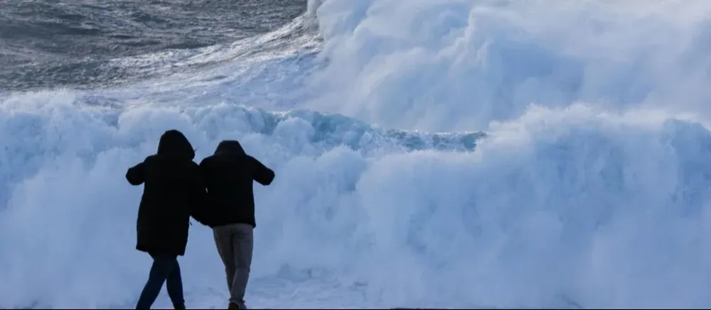 Dos turistas observan el oleaje en la costa de Muxía, este miércoles en A Coruña
