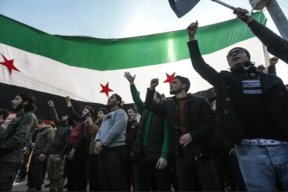 Manifestantes levantan banderas y pancartas de la oposición siria mientras protestan contra un posible acercamiento entre Ankara y el régimen sirio