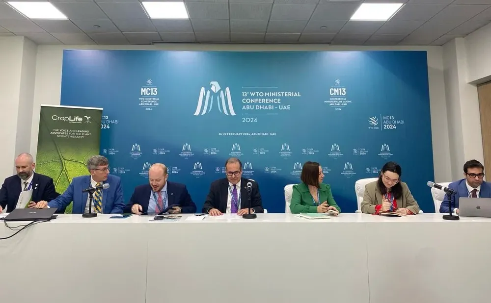 En la mesa principal: Brodie Berrigan, Representante de la Organización Mundial de Agricultores; Jason Hafemeister, Subsecretario en Funciones de Comercio y Asuntos Agrícolas Internacionales de Estados Unidos; Julio Ramos, Subsecretario de Comercio y Relaciones Internacionales del Ministerio de Agricultura y Ganadería de Brasil; Lloyd Day, Subdirector General Sud del IICA; Emily Rees, Presidenta y CEO de CropLife International; Sofía Boza, Embajadora Permanente de Chile ante la OMC y Martín Alvez, Delegado Agrícola de la Embajada de Uruguay ante la OMC.