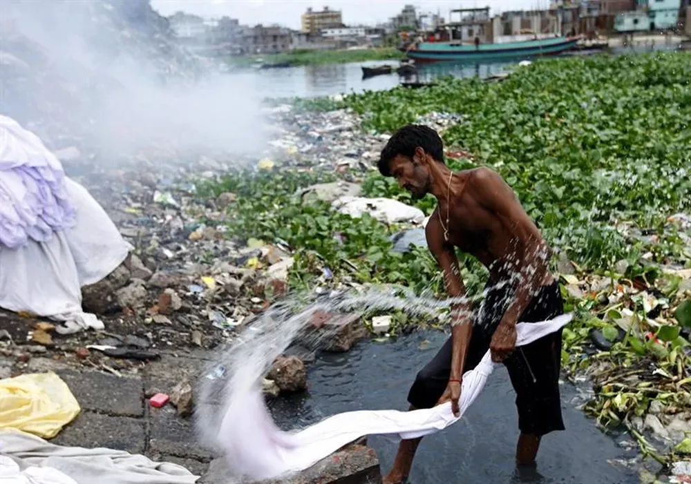 Un lavandero bengalí lava ropa en las contaminadas aguas del río Buriganga en Dacca (Bangladesh)