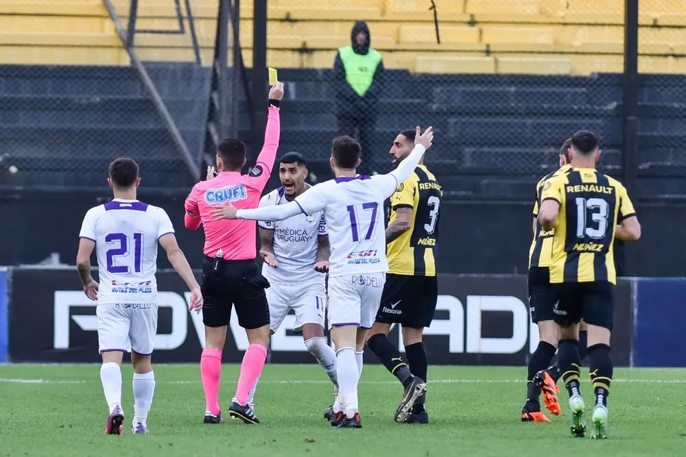 Mathías De Armas le saca la amarila a Rak, semitapado, ante la protesta de Balboa y de sus compañeros de Defensor Sporting