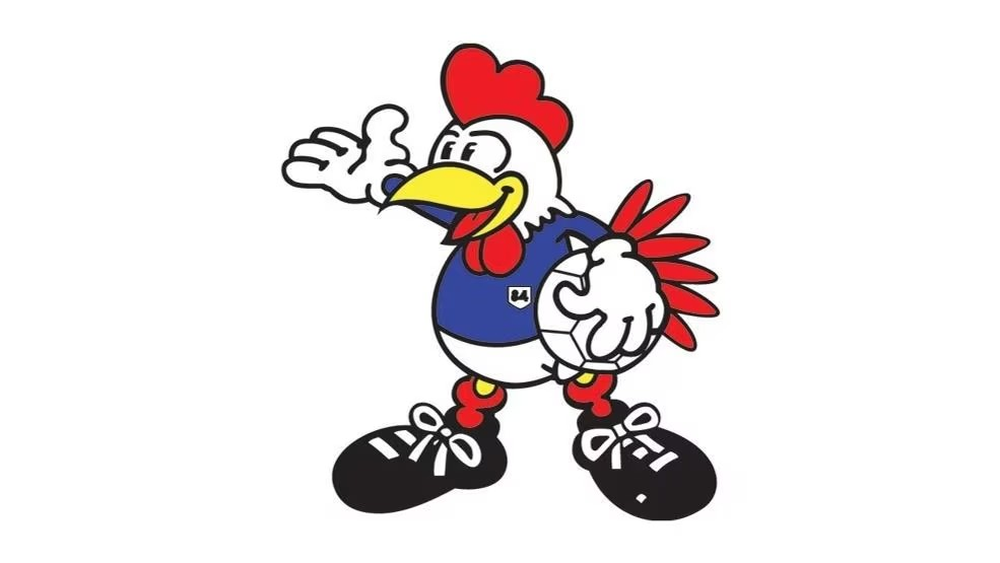 Péno (Francia 1984): Péno, el gallo francés, destaca en su traje azul, blanco y rojo, simbolizando la elegancia y la tradición francesa en el fútbol.